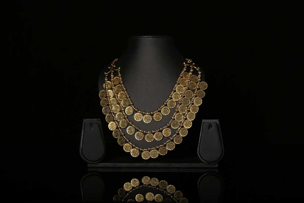 Goldener Schmuck aus Münzen auf schwarzer Büste